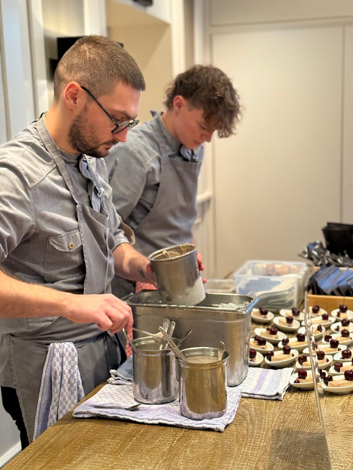 Küchenteam Zwei Männer in grauen Schürzen beim Kochen.