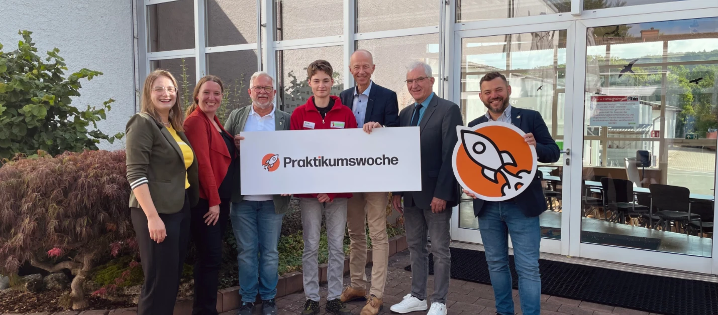 Praktikumswoche 2025 Eine Gruppe von Menschen hält Schilder.