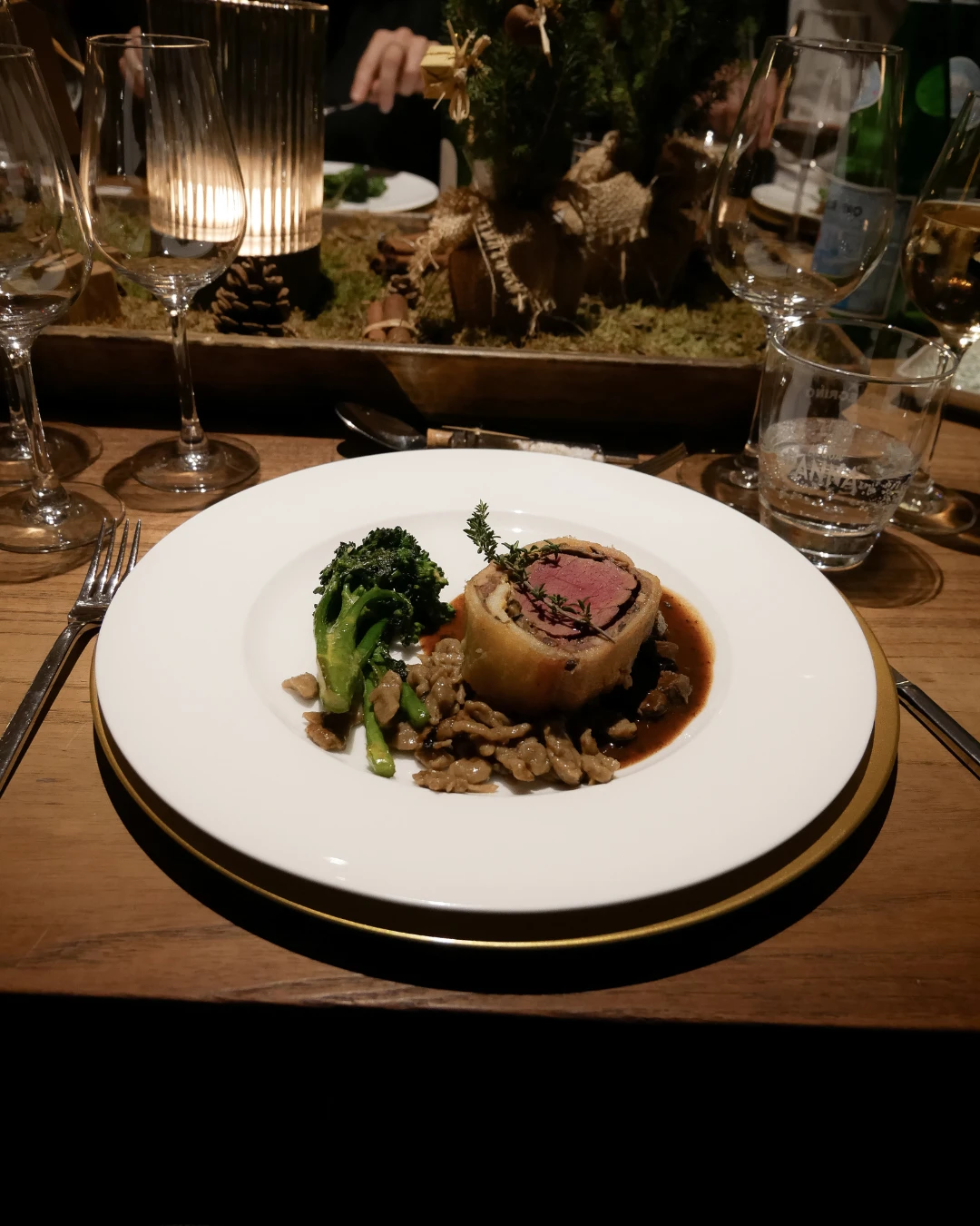 Ein Teller mit Essen auf einem Tisch in einem Restaurant mit Weinglas.