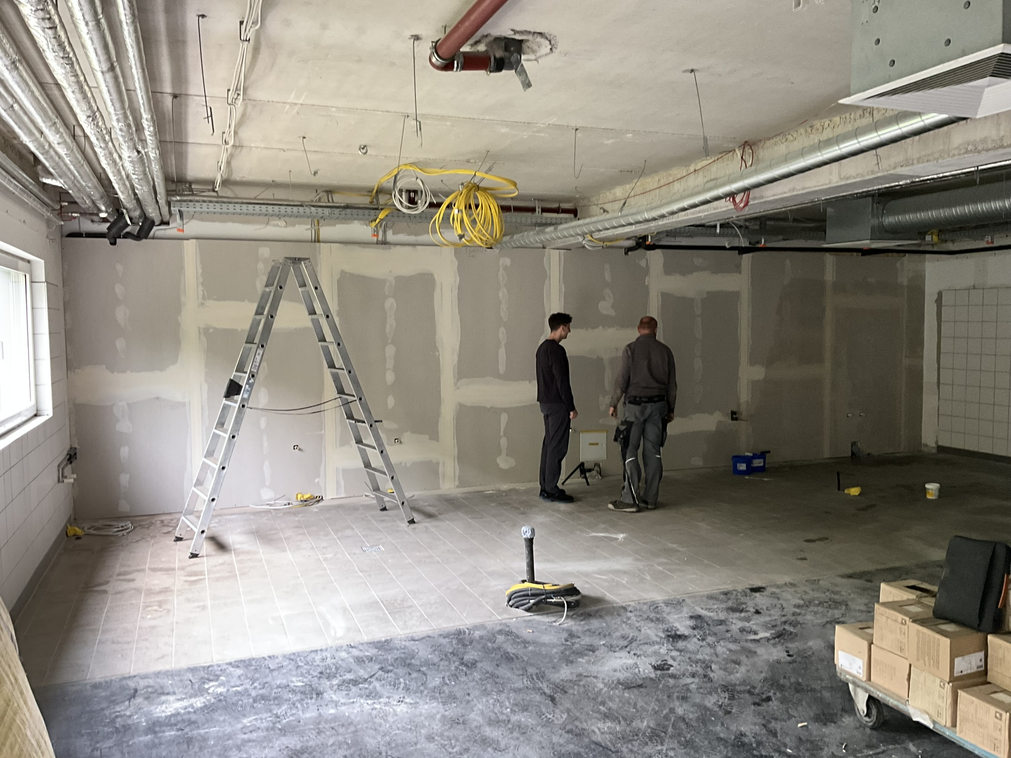 Neuwerk Continental Korbach Zwei Männer stehen in einem Raum mit Leitern.