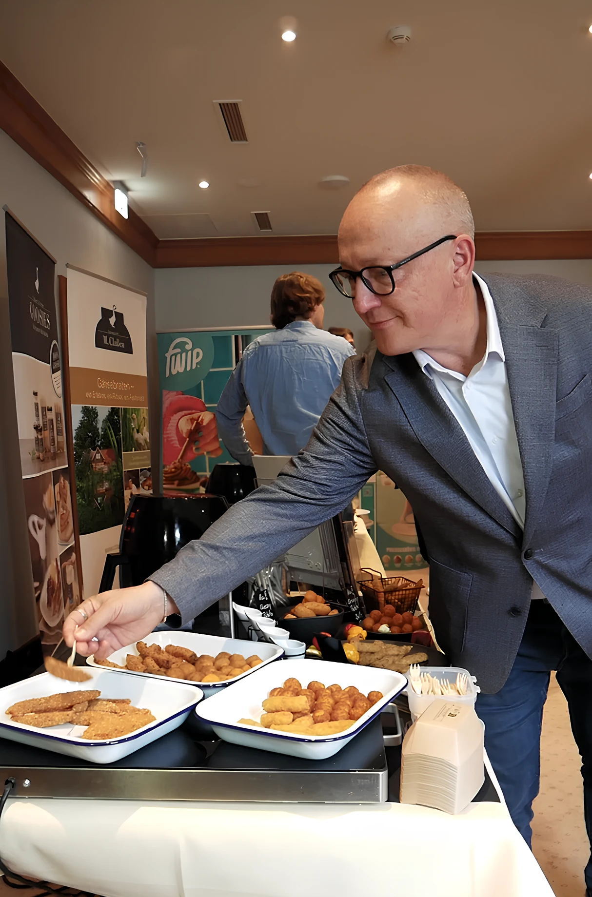 Lieferantenmeeting Oktober 2025 Ein Mann im Anzug richtet Essen auf einem Tisch an.