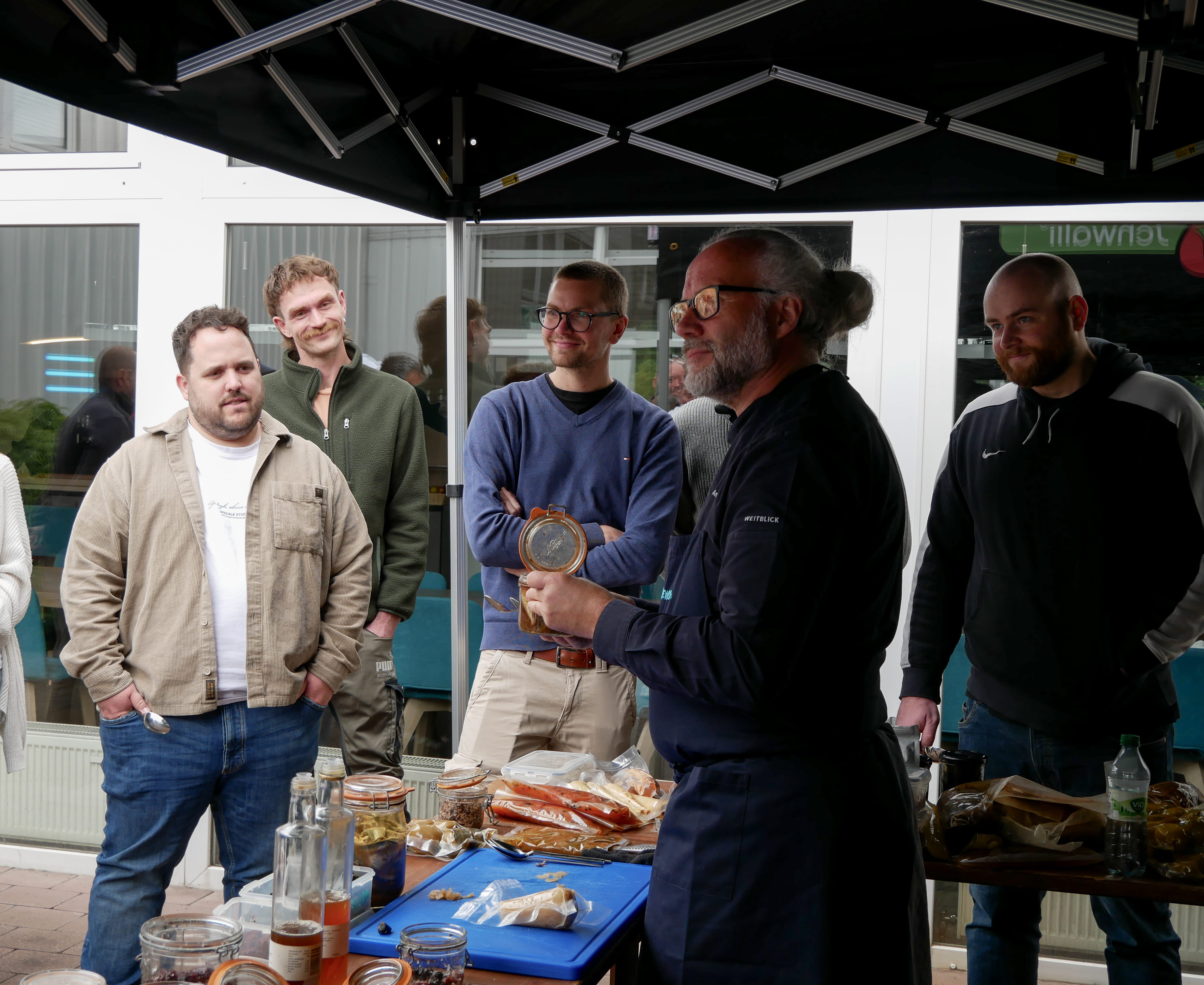 Fermentation & Umami Eine Gruppe von Männern steht um einen Tisch mit Essen.
