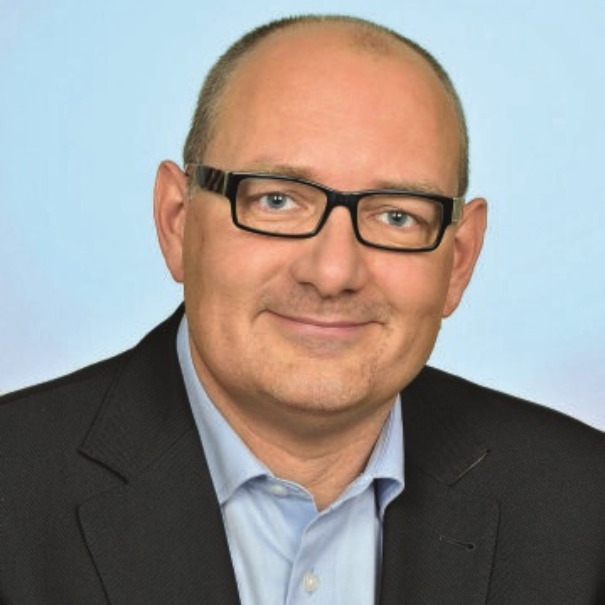 Sven-Uwe Kempe Ein Mann mit Brille und Anzug lächelt.