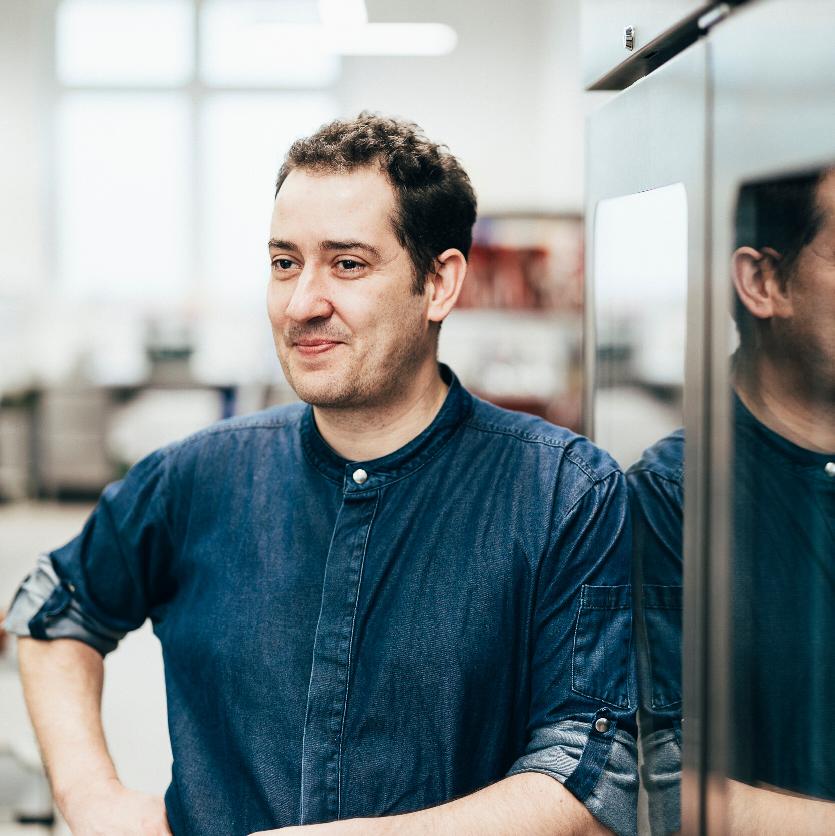 Falk Millisterfer Ein Mann mit Brille und Bart steht lächelnd in einer Küche.