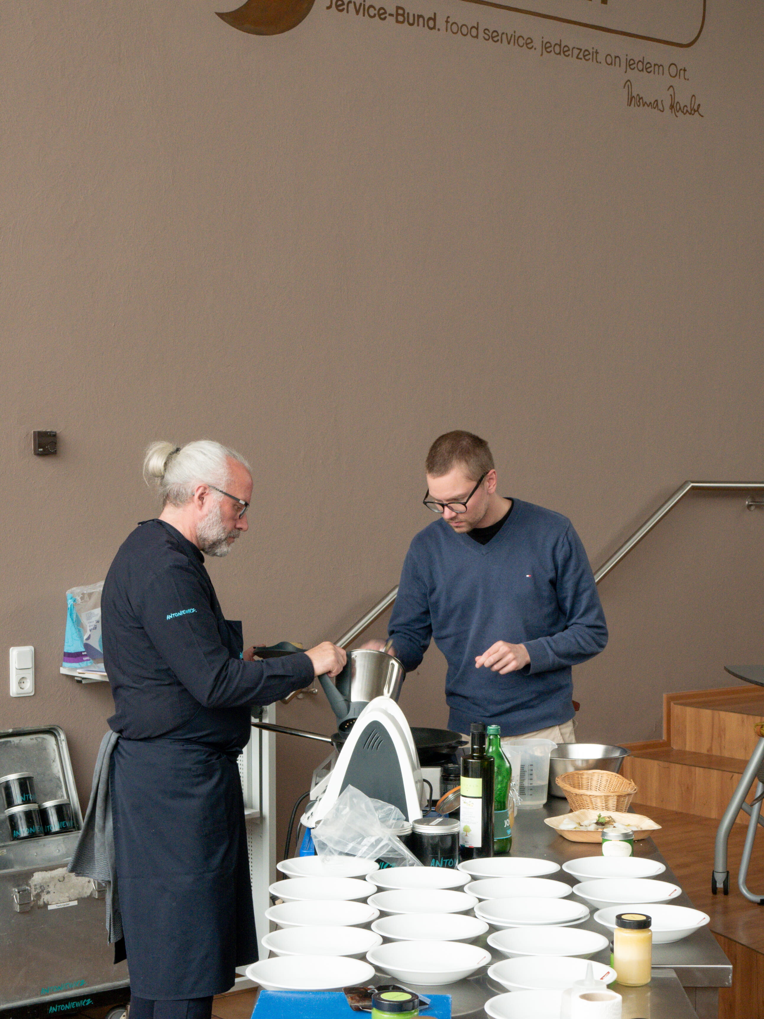 Fermentation & Umami Eine Gruppe von Männern steht um einen Tisch mit weißen Schüsseln.