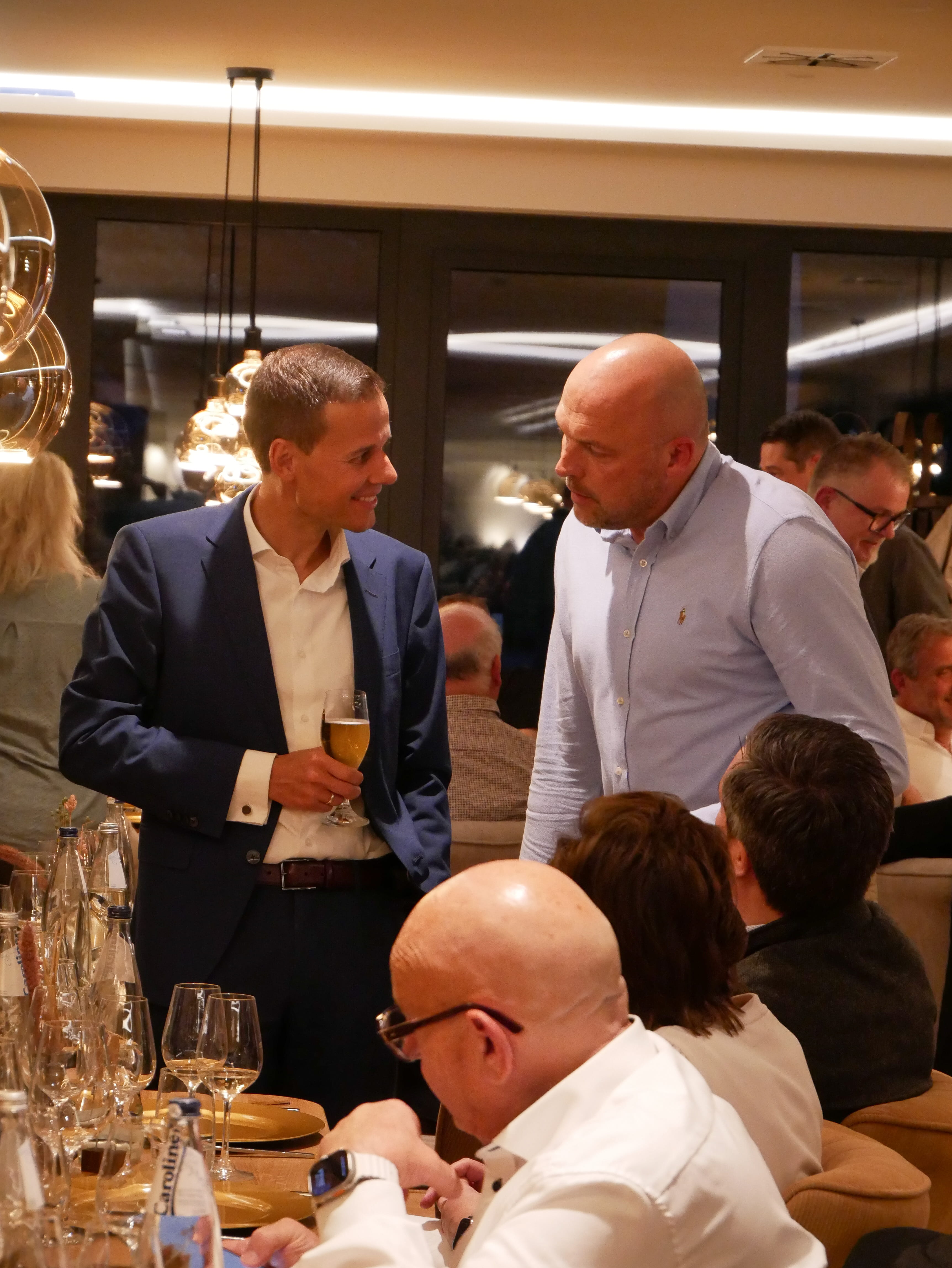 Zwei Männer stehen an einem Tisch mit einem Glas Champagner.