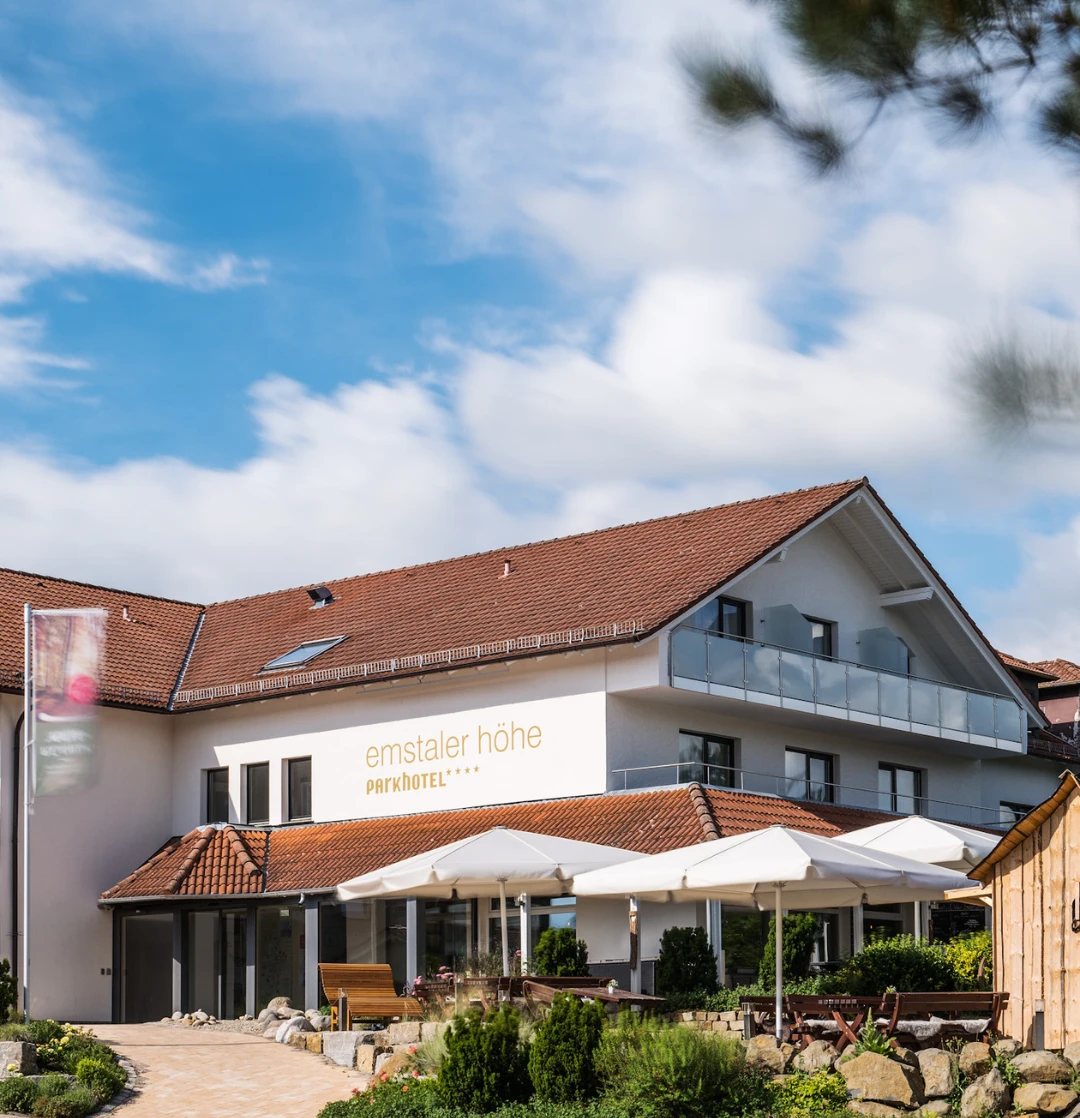 Hotel 4 Sterne Ein Gebäude mit rotem Dach und weißen Sonnenschirmen.
