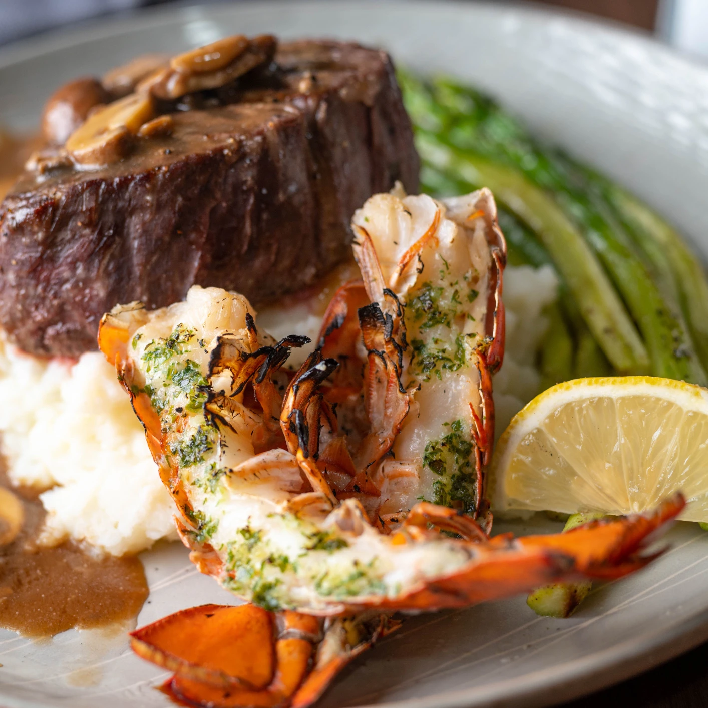 Surf & Turf vom Grill Ein Teller mit einem Stück Fleisch und Hummer.