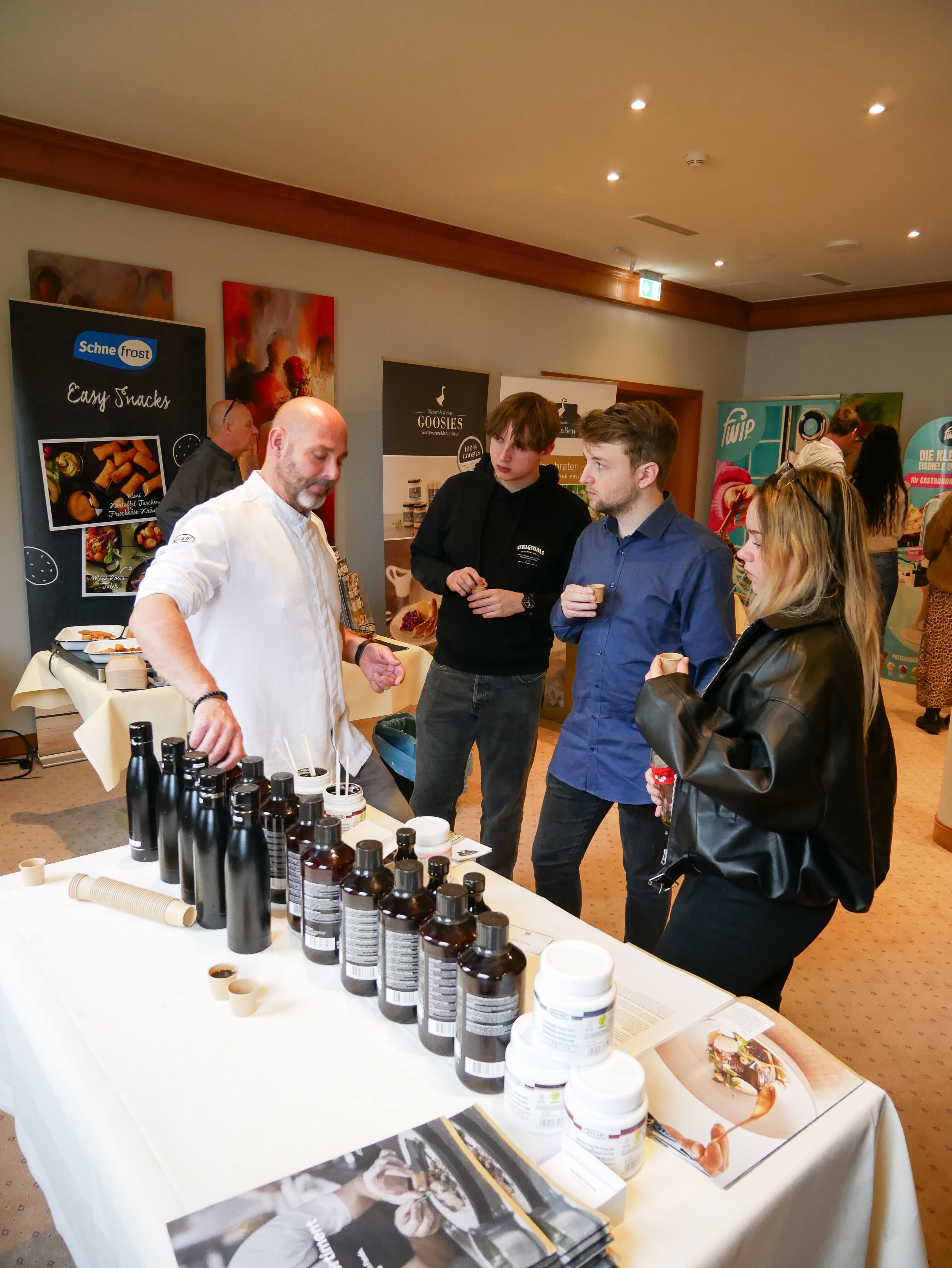 Lieferantenmeeting Oktober 2025 Eine Gruppe von Menschen steht um einen Tisch mit Flaschen.