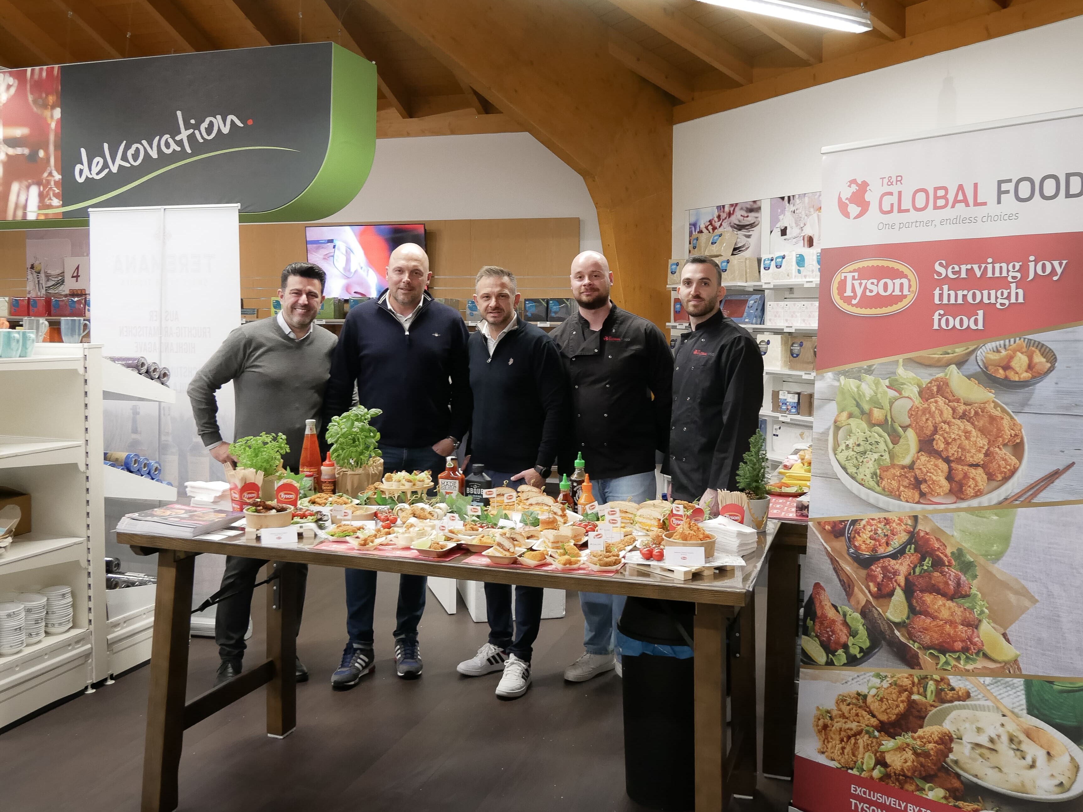 Lieferanten Meeting 112025 Eine Gruppe von Männern steht vor einem Tisch mit Lebensmitteln.