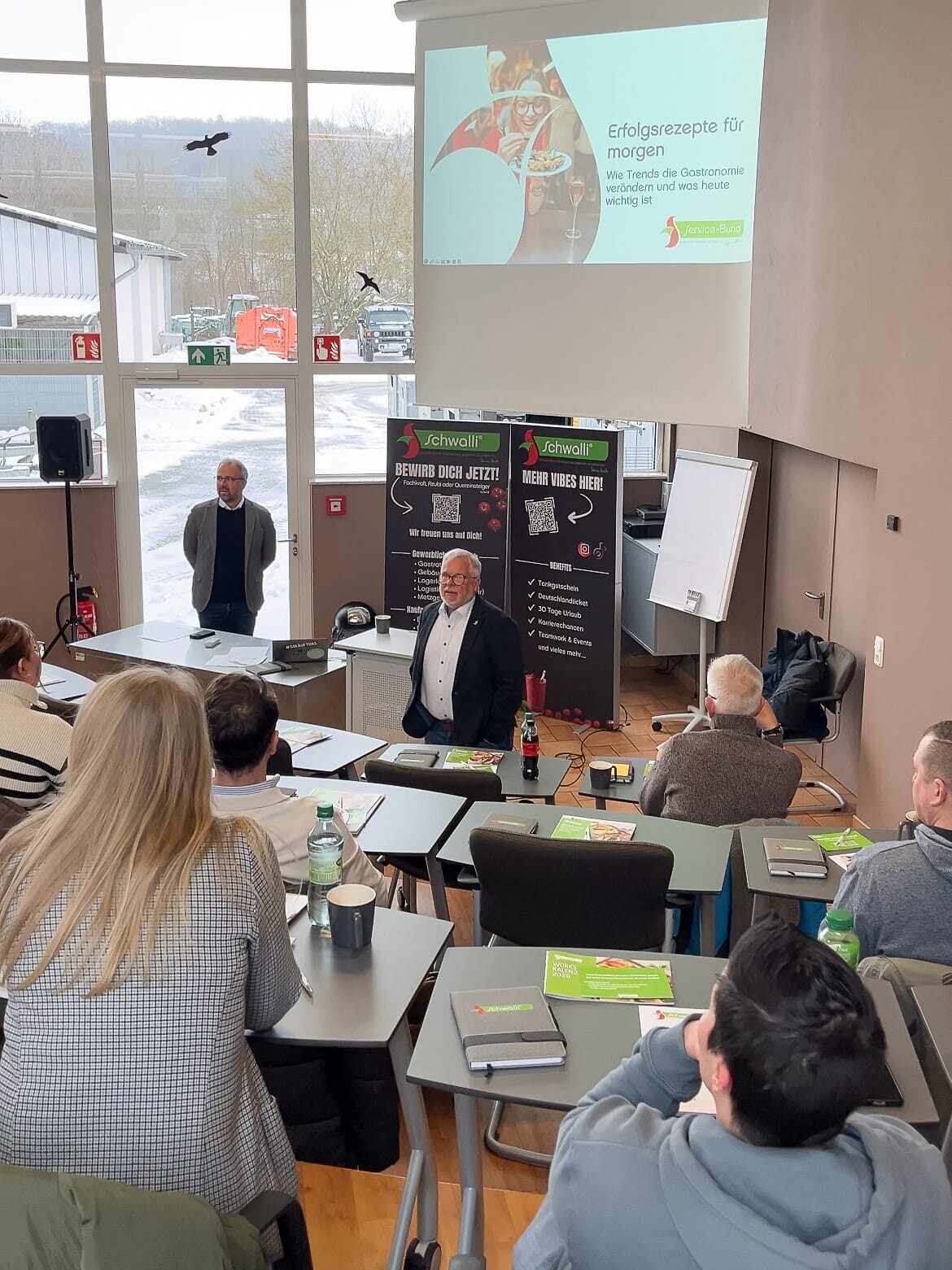 Erfolgsrezepte für morgen Ein Mann steht vor einer Gruppe von Menschen in einem Klassenzimmer.