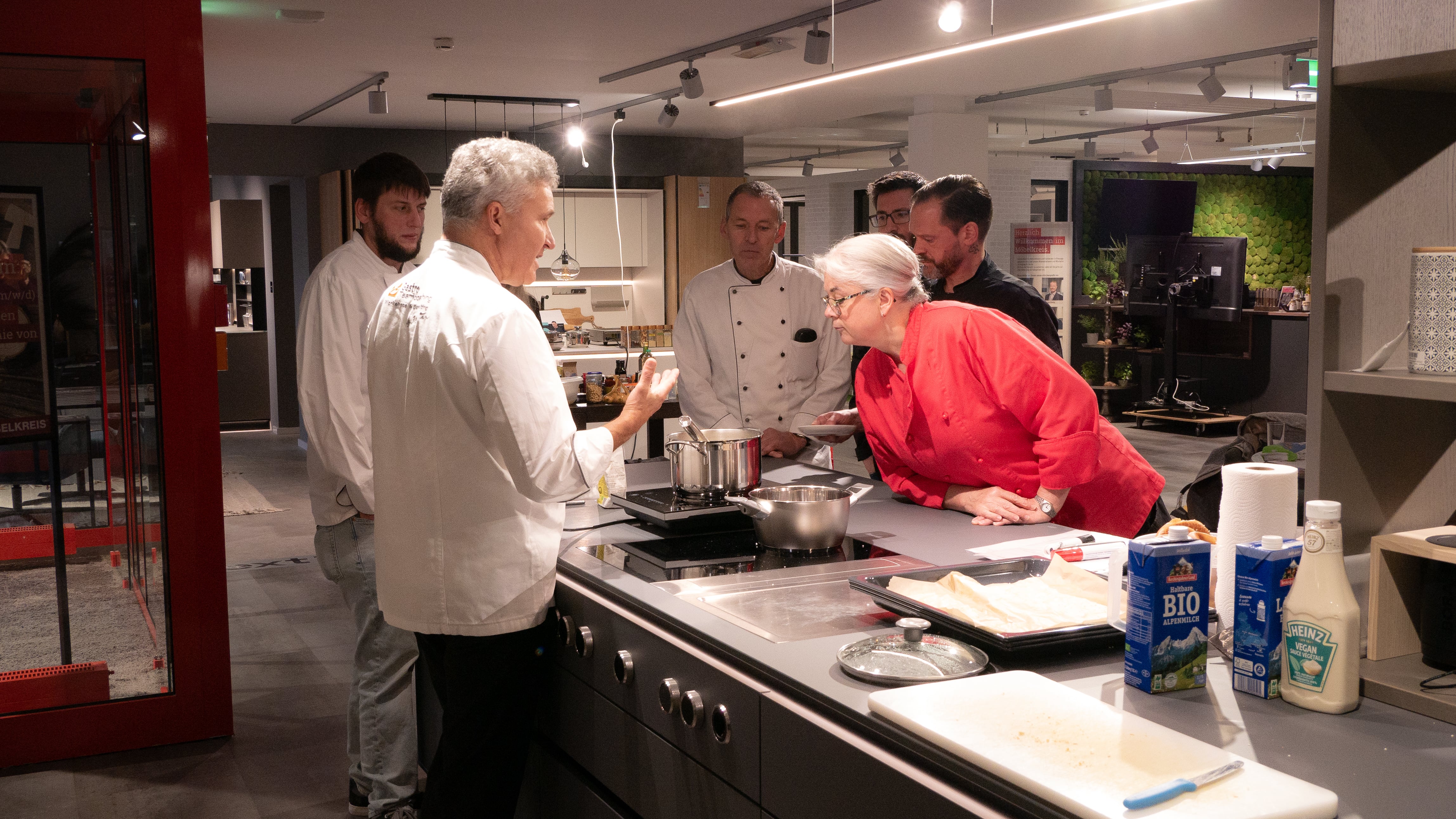 Gesunde Ernährung in der GV Eine Gruppe von Menschen steht um einen Tresen.