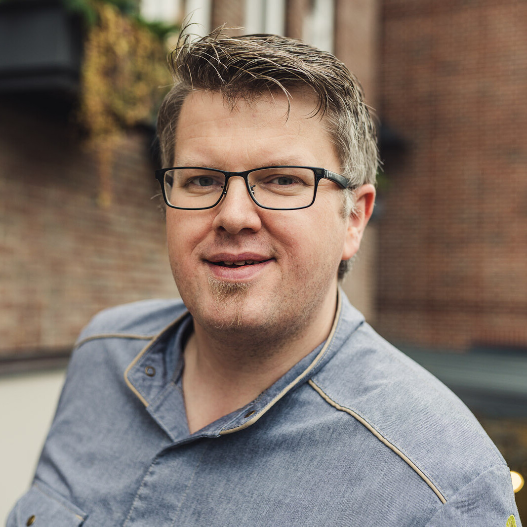 Erik Arnecke Ein Mann mit Brille und blauem Hemd lächelt.