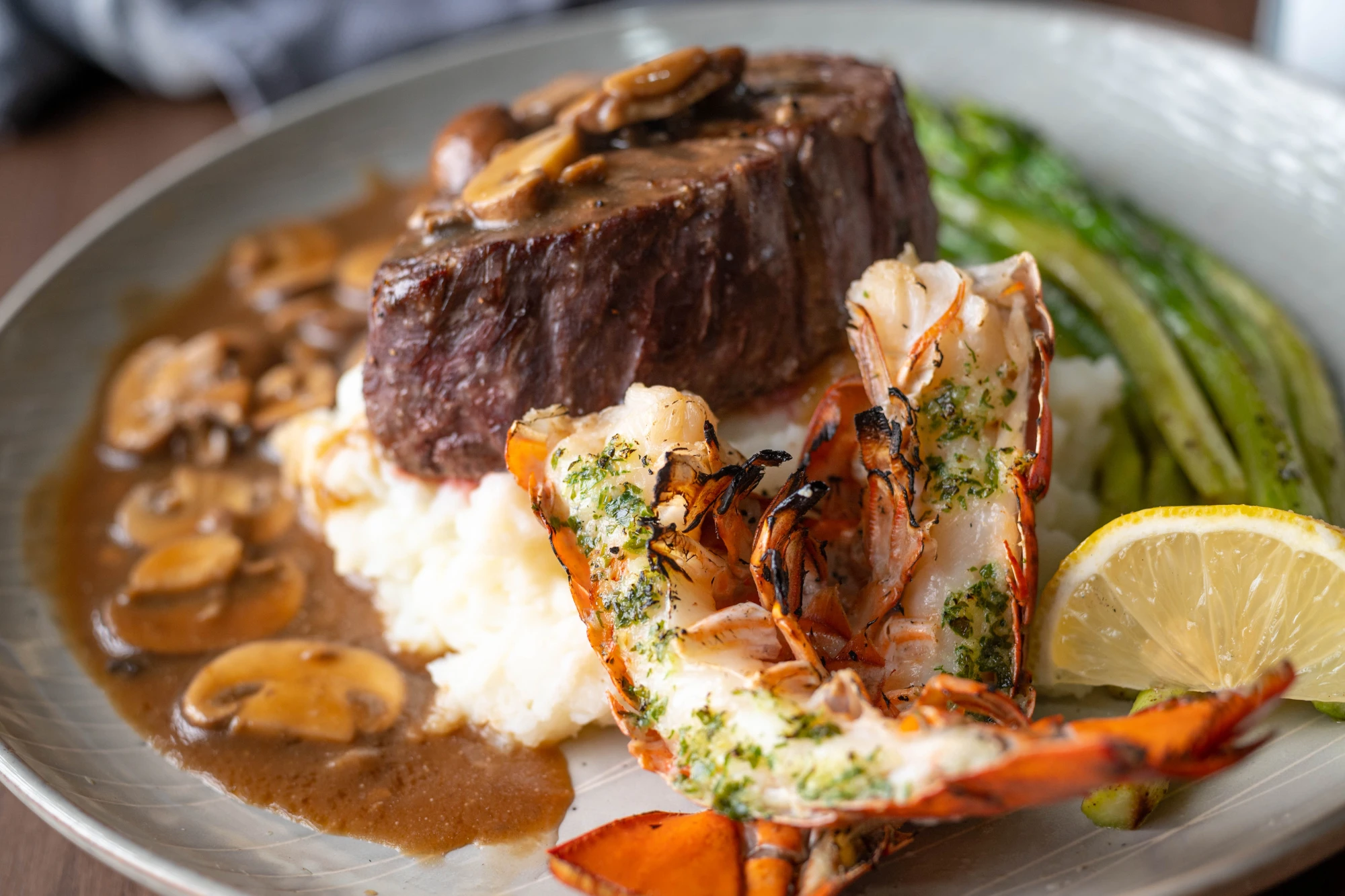 Surf & Turf vom Grill Ein Teller mit einem Stück Fleisch und Hummer.