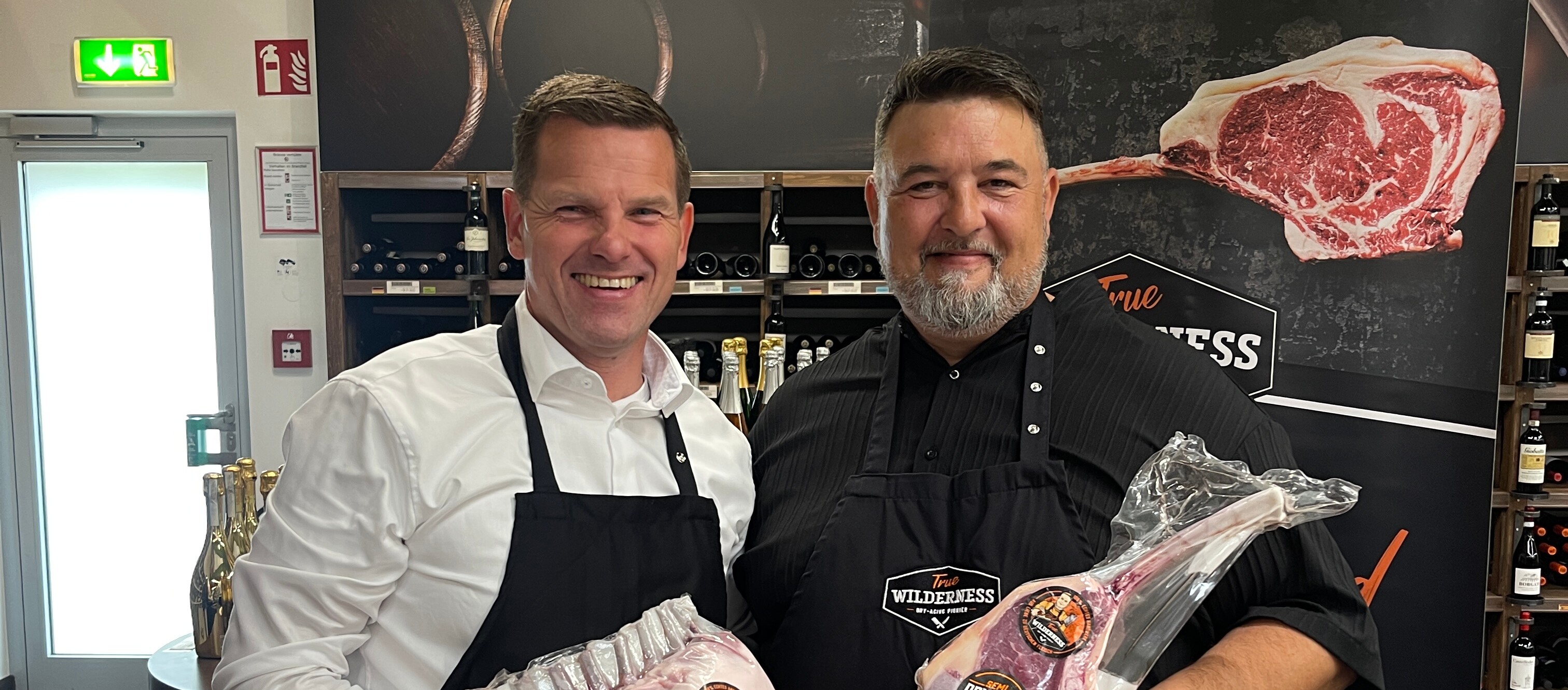Zwei Männer halten Fleisch in ihren Händen.