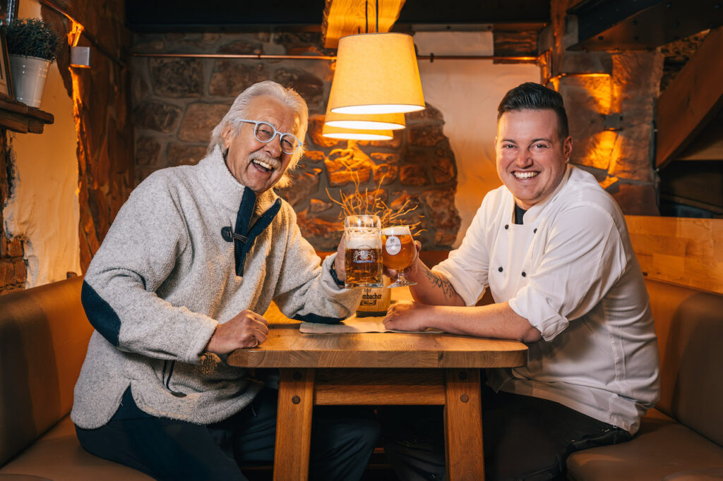 Gartenlaube Marburg Zwei Männer sitzen an einem Tisch und halten Biergläser.