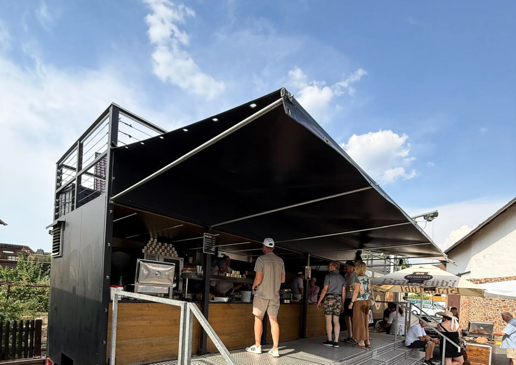 Menschen stehen vor einem Foodtruck im Freien