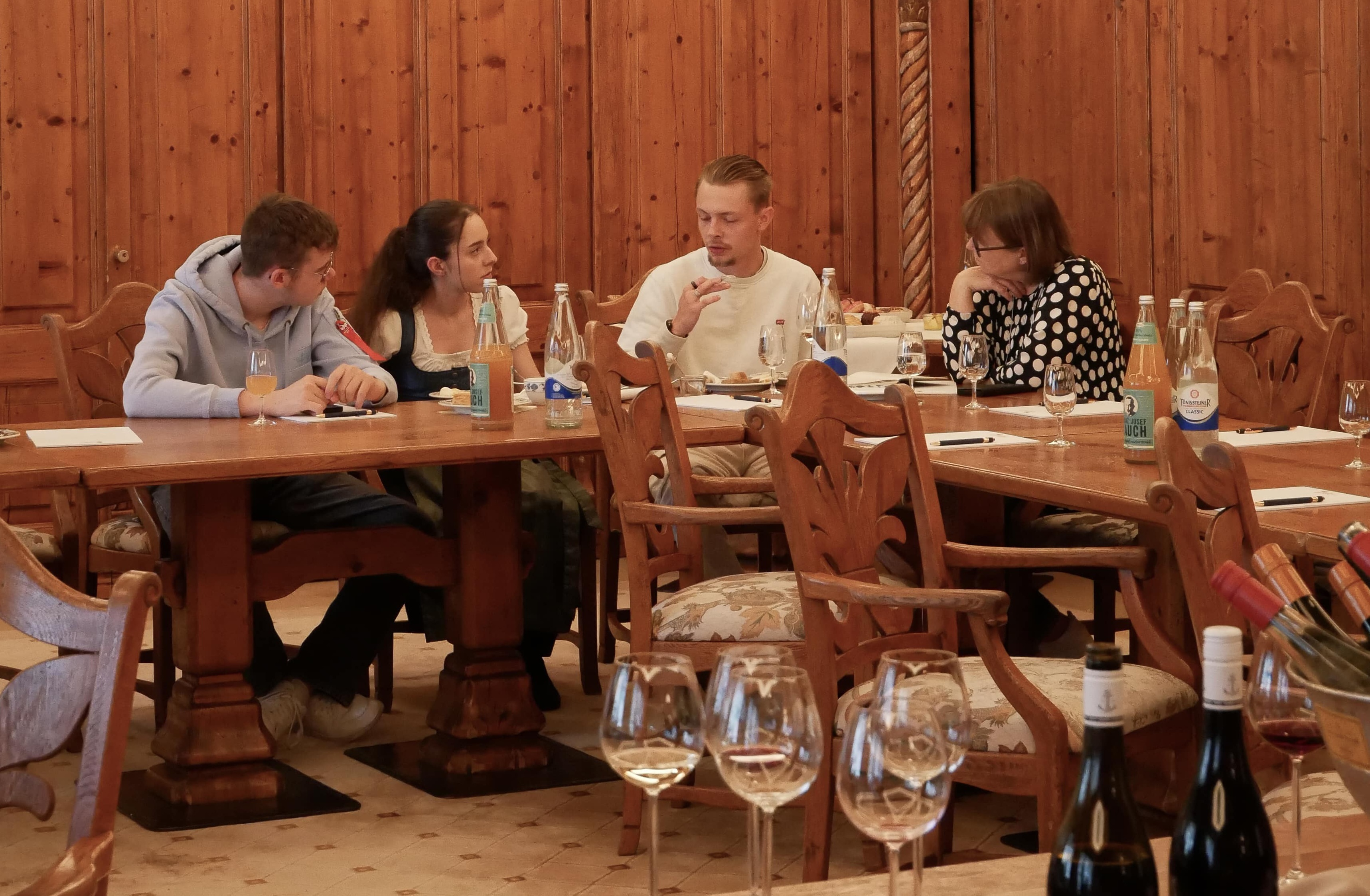 Käse-Seminar Eine Gruppe von Personen sitzt an einem Tisch mit Wein und Gläsern.