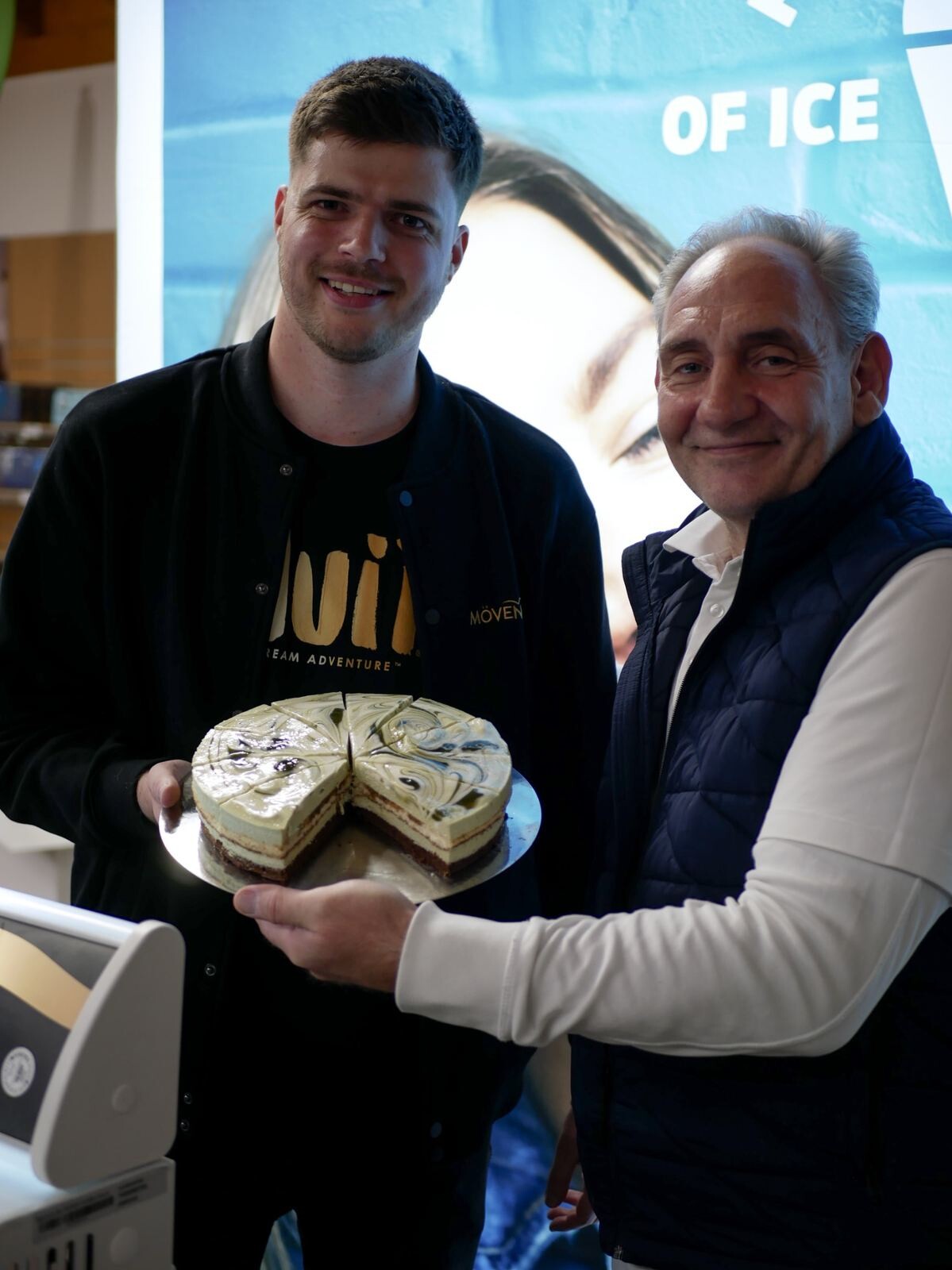 Ein Mann hält einen Kuchen und lächelt.