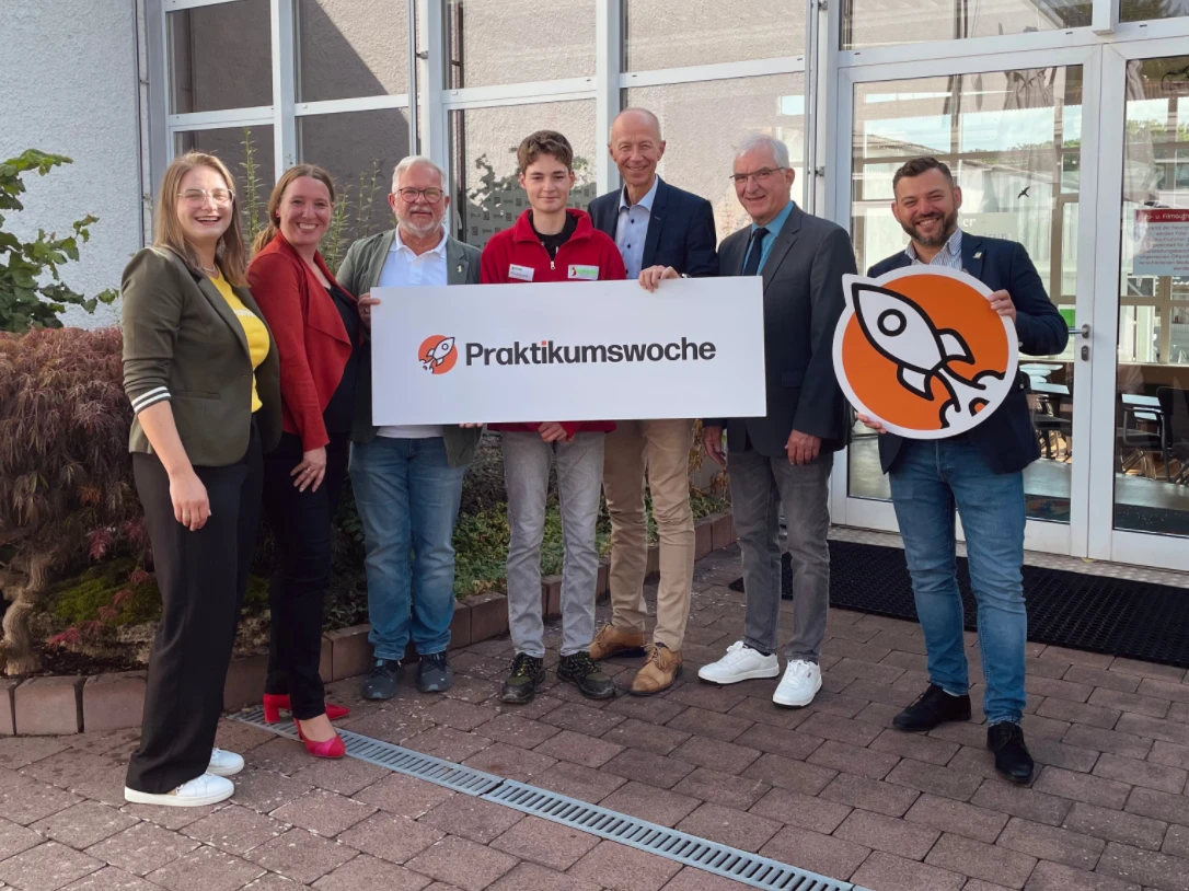 Praktikumswoche 2025 Eine Gruppe von Menschen hält Schilder.