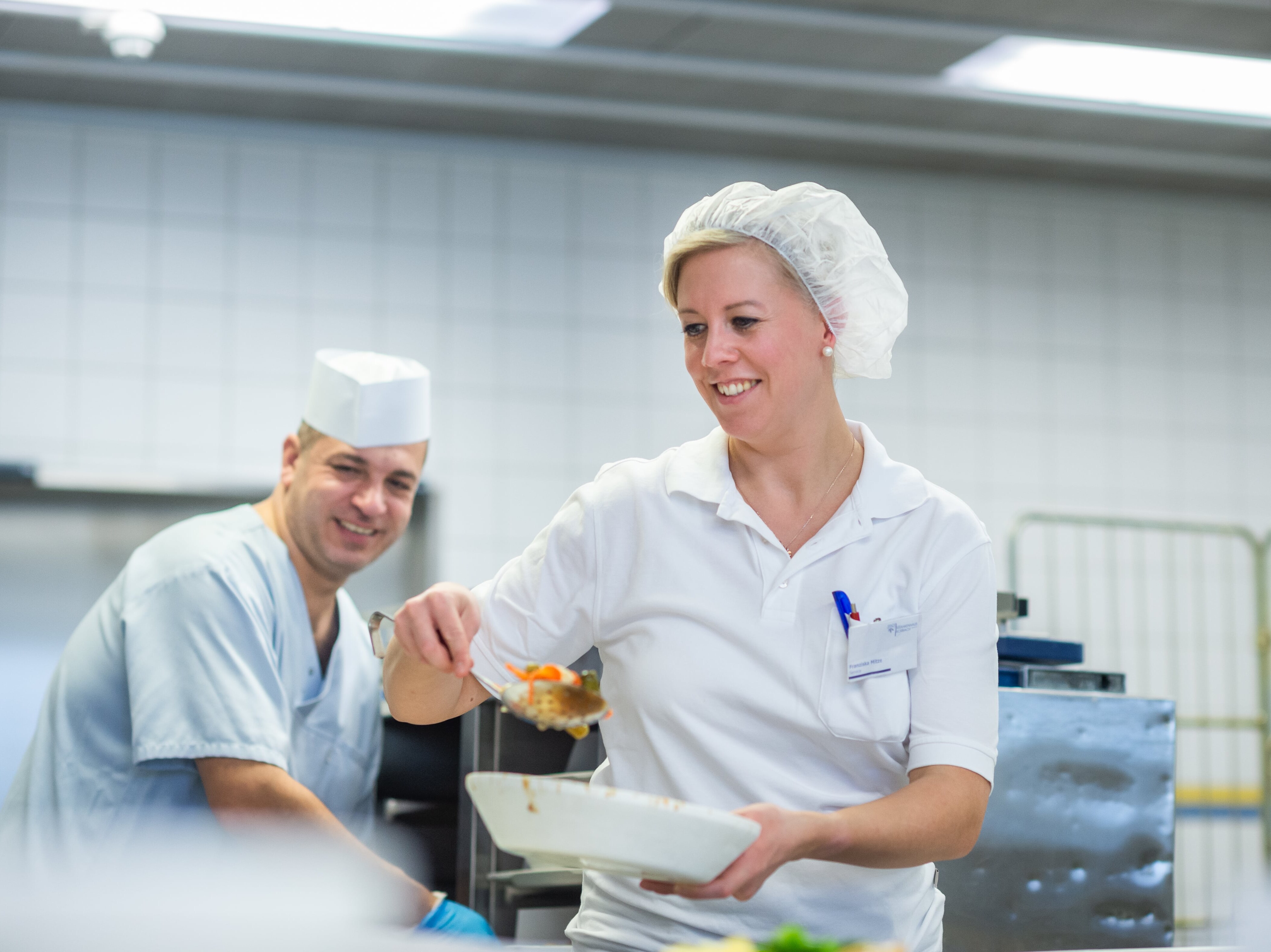 Eine Frau in weißer Uniform hält eine Schüssel mit Essen.