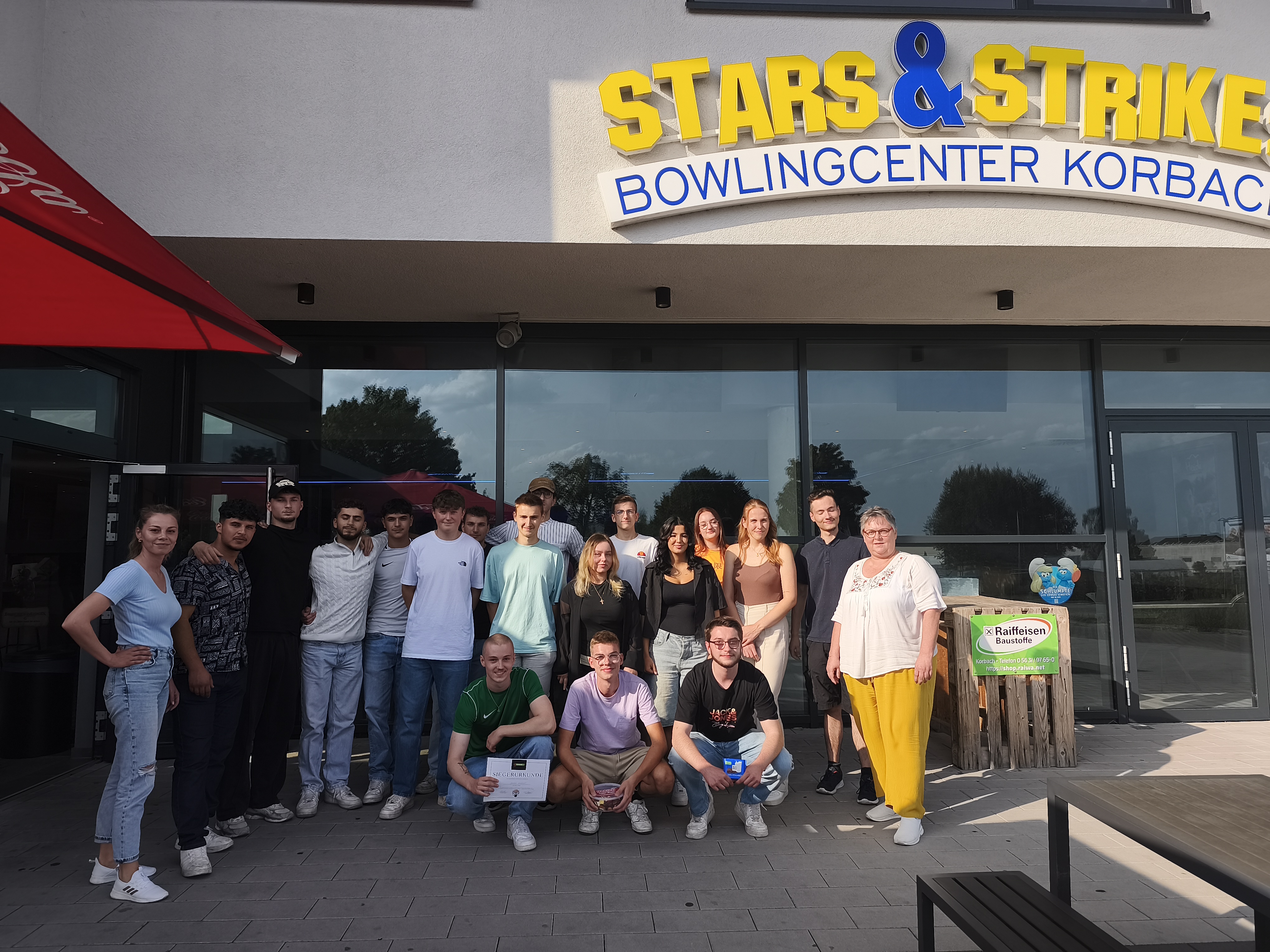 Eine Gruppe von Menschen posiert für ein Foto vor einem Gebäude.