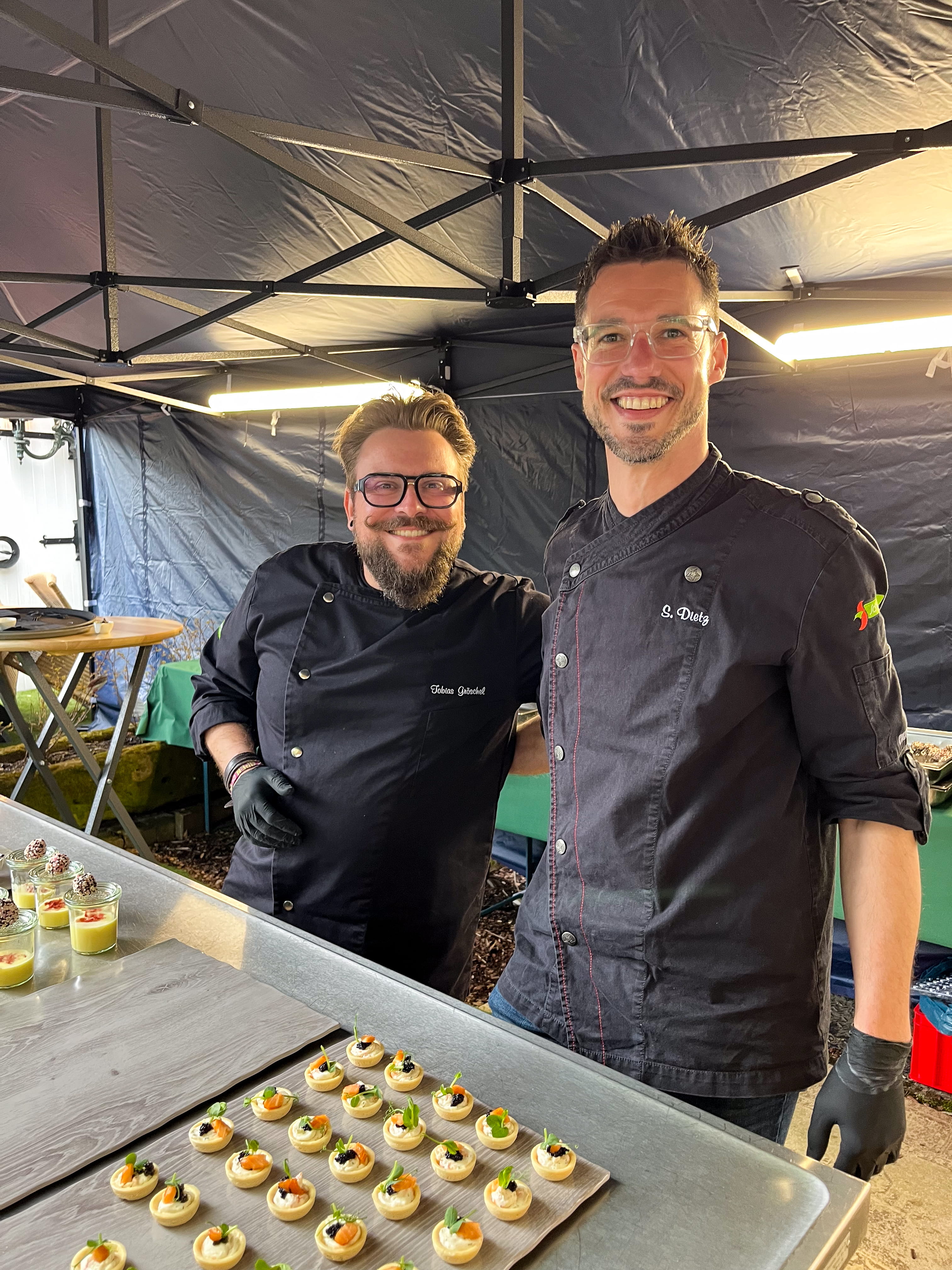 Zwei Männer stehen nebeneinander und lächeln.