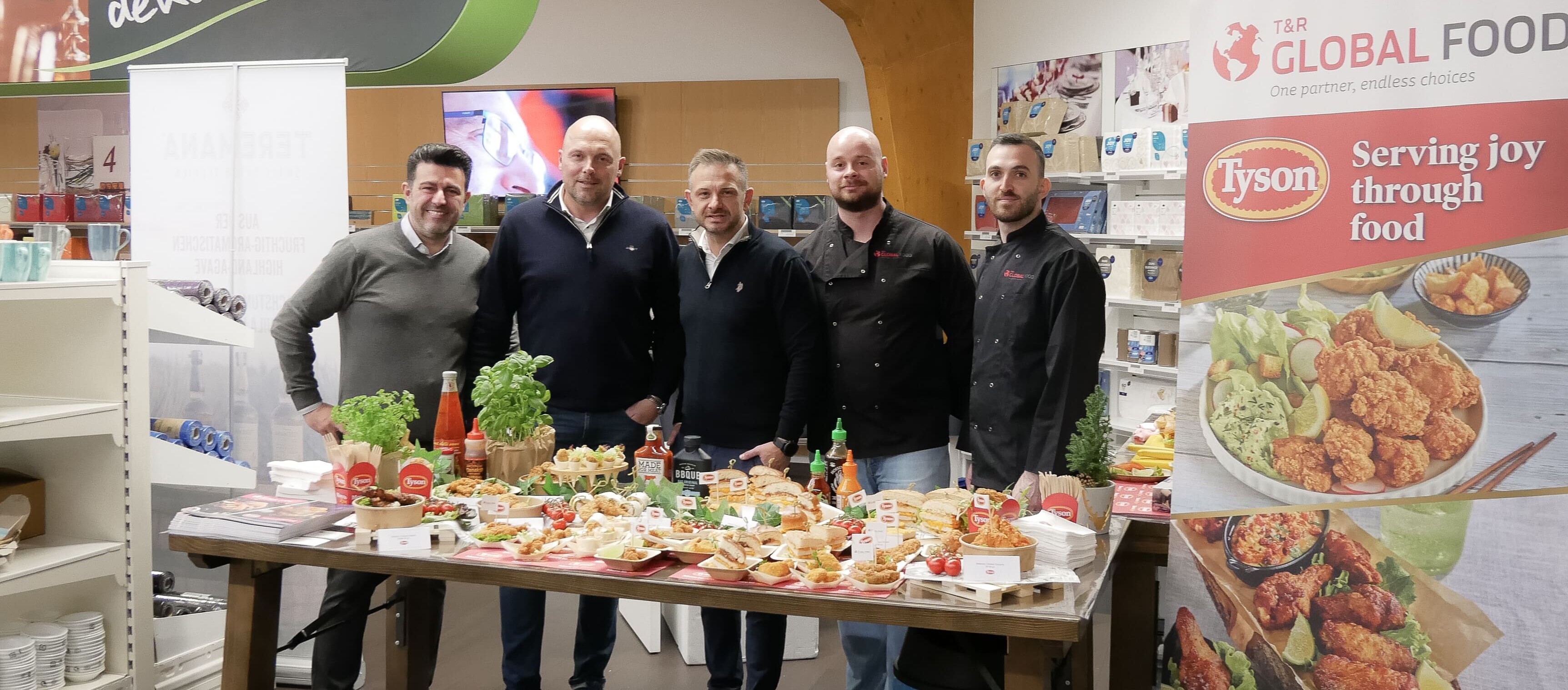 Eine Gruppe von Männern steht vor einem Tisch mit Lebensmitteln.