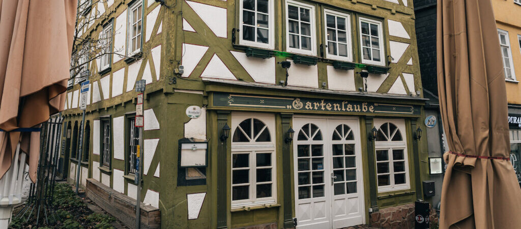 Gartenlaube Marburg Ein Gebäude mit grün-weißer Fassade und Fenstern.
