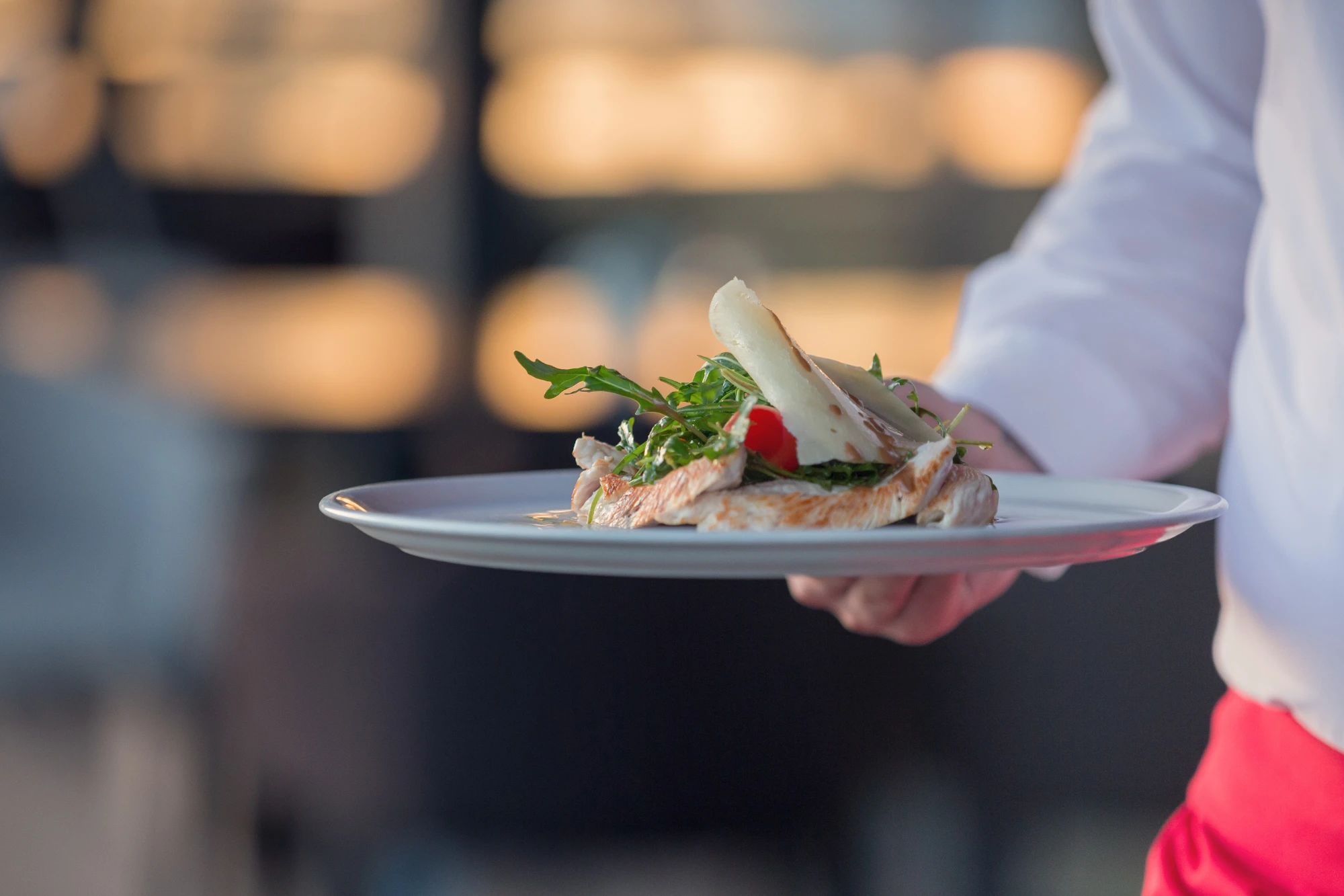 Eine Person hält einen Teller mit Fast Food und Meeresfrüchten.