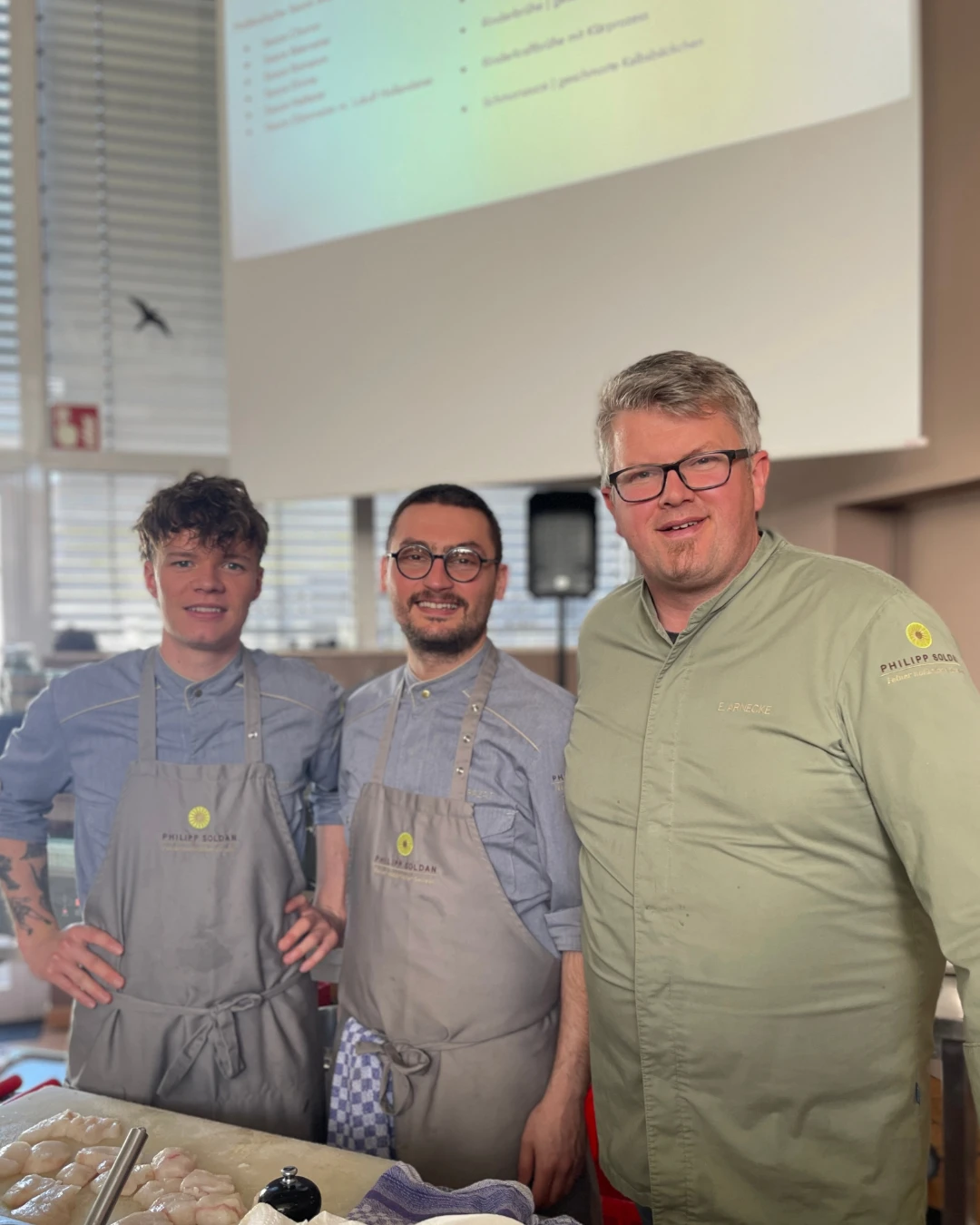 Eine Gruppe von Männern in Schürzen lächelt.